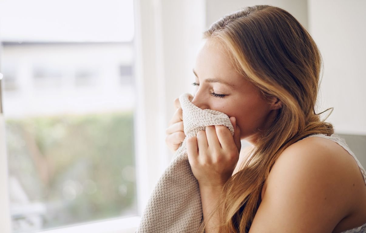Una donna avvicina al viso un asciugamano morbido appena lavato